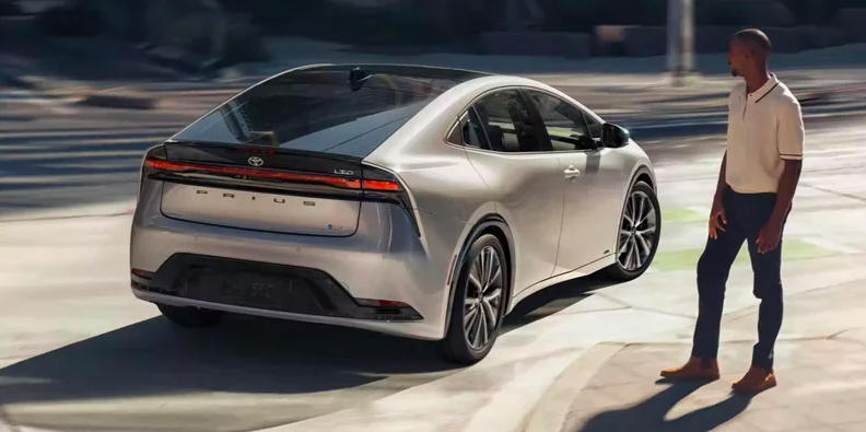 A man looking at a2024 Toyota Prius as it makes a turn.