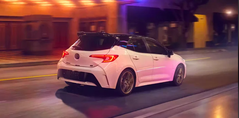 A white 2024 Toyota Corolla Hatchback driving down a road.