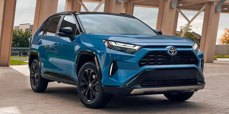 A blue 2024 Toyota RAV4 plug-in Hybrid parked in a driveway.