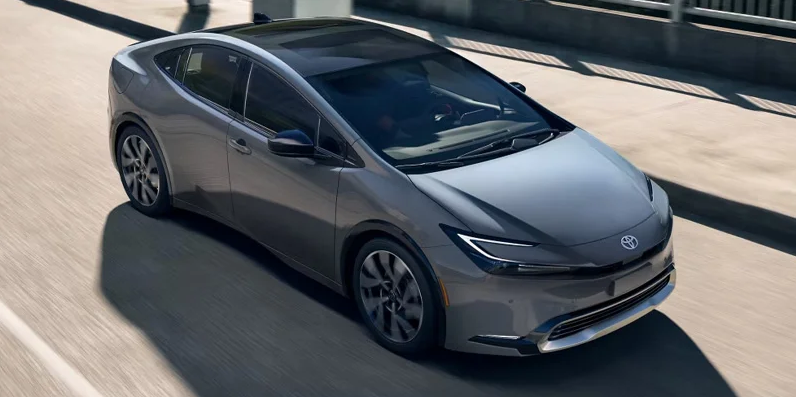 A photo of a 2025 Toyota Prius plug-in-hybrid driving down a road.