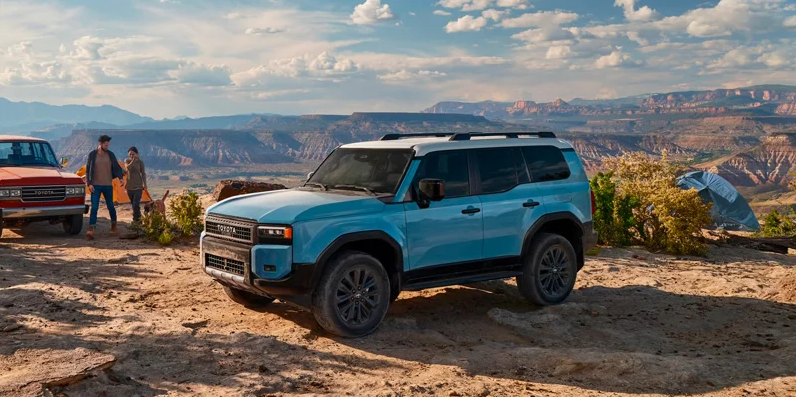 A photo of a blue 2025 Toyota Land cruiser parked near a campsite.