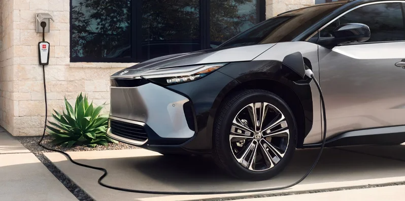 A 2025 Toyota bZ4X plugged in charging in a driveway.