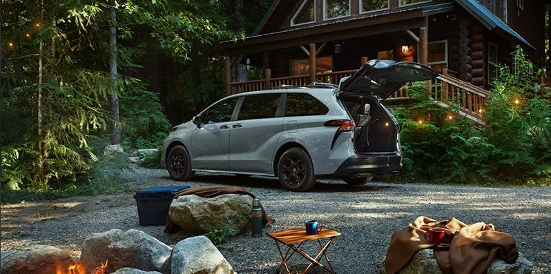 A silver 2025 Toyota Sienna parked in front of a cabin. 