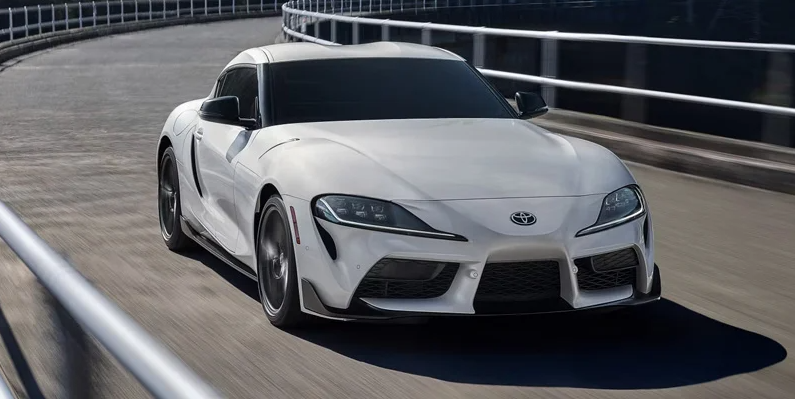 A 2026 Toyota GR Supra driving down a road.