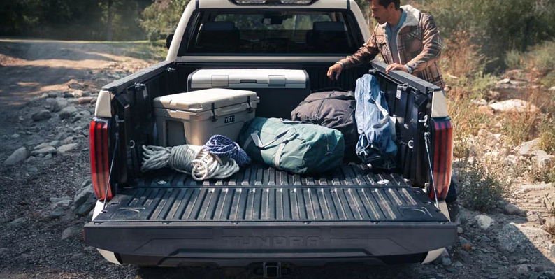 A man loading camping gear in to the back of a 2026 Toyota Tundra.