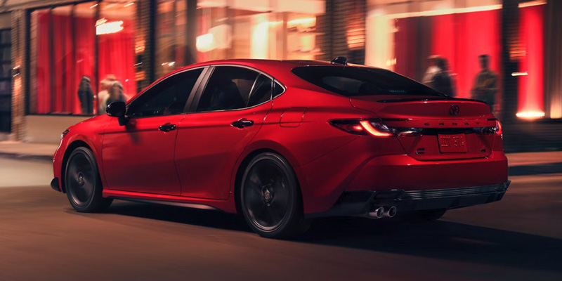 Red 2026 Toyota Camry driving through city streets at night