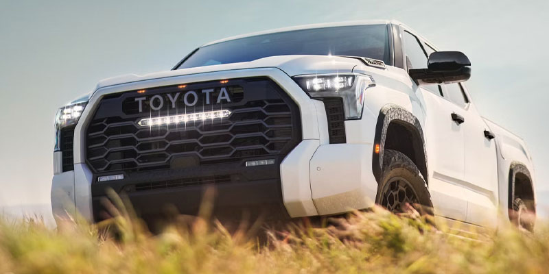 White 2026 Toyota Tundra driving off-road through grassy terrain